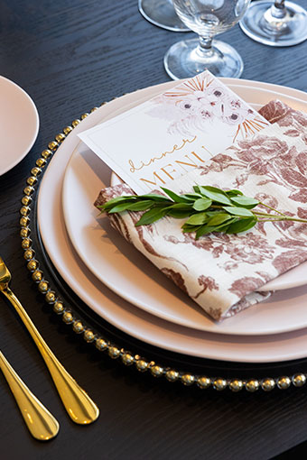 Wedding Reception table set up with flower cloth napkin with menu tucked inside and gold flatware