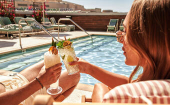 two guests cheers by the pool with cocktails at Kimpton Hotel Palomar Phoenix
