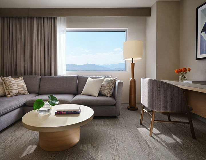 Kimpton Hotel Palomar Phoenix Suite Living Area with sofa, coffee table, chair, desk, lamp and view of mountains after renovation